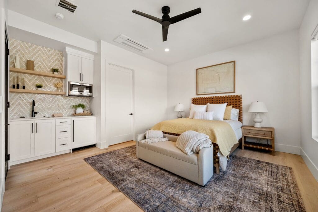Bright, inviting bedroom featuring upscale furnishings, a cozy seating area, and a stylish kitchenette in a modern living space.