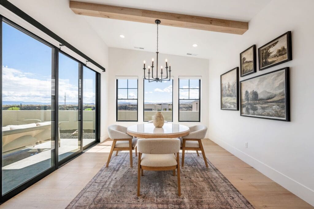 Bright dining area with modern decor, large windows showcasing scenic views, and a stylish round table with plush chairs.