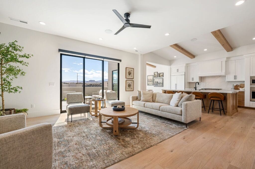 Bright, airy living room showcasing upscale furnishings, large windows with mountain views, and modern kitchen amenities.