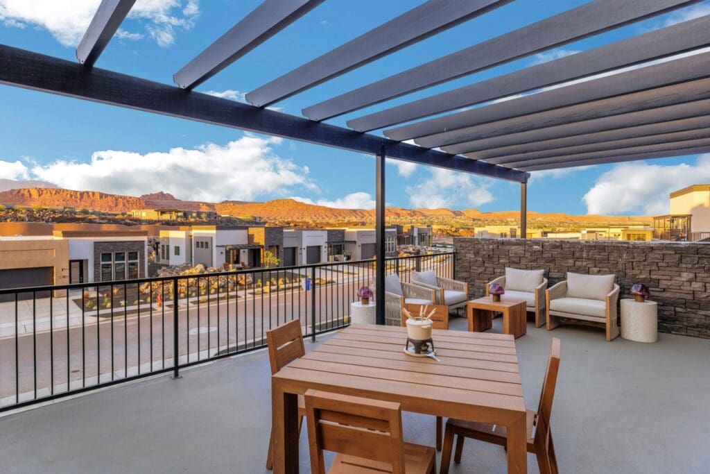 Charming outdoor terrace featuring stylish seating and a dining table, with stunning mountain views and vibrant, blue skies.