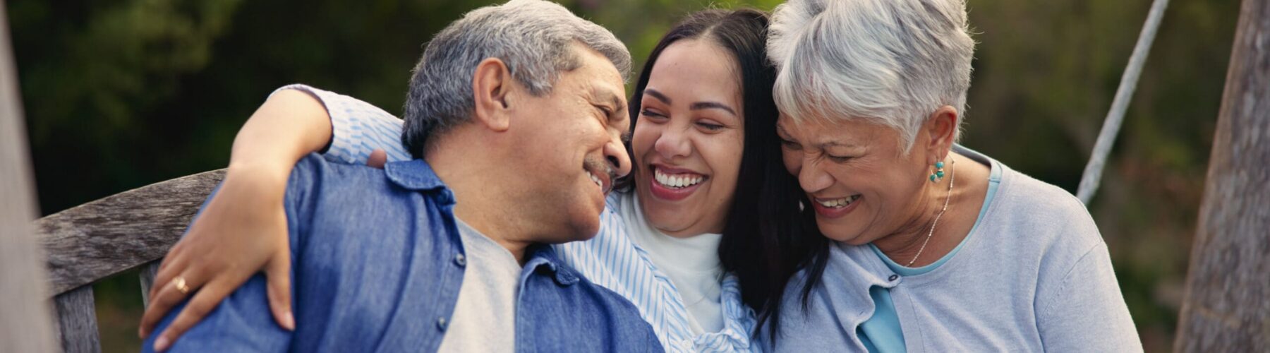 A joyful moment with two seniors and a young woman, sharing laughter in a serene outdoor setting.
