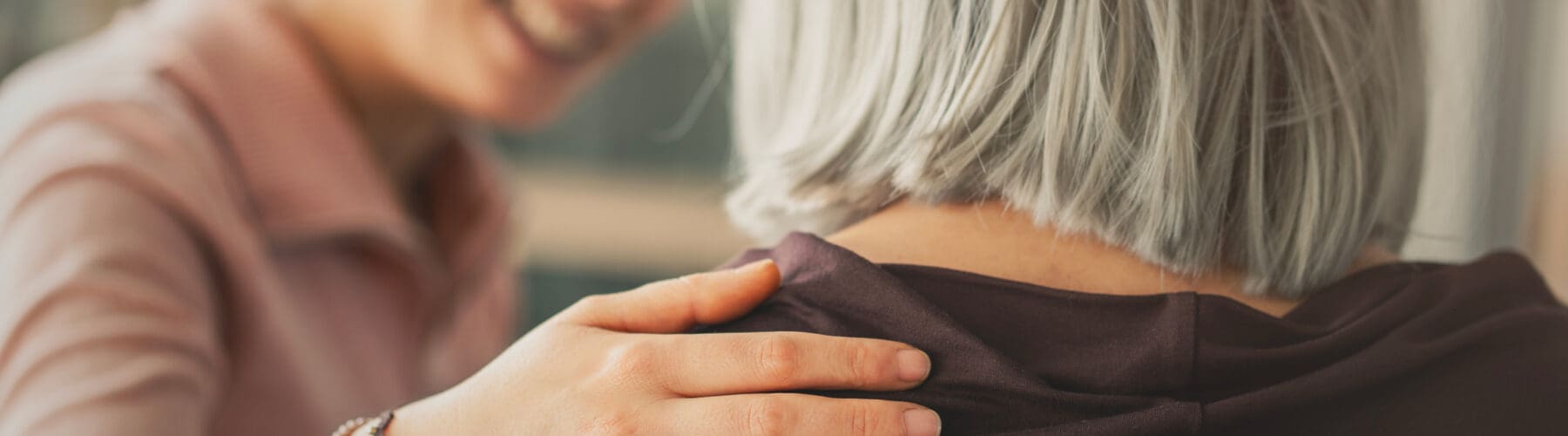 A caregiver gently comforts a senior woman, fostering a warm moment of connection and compassionate support.