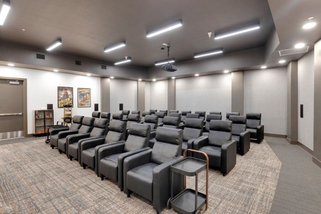 Upscale theater room featuring plush black reclining chairs, elegant lighting, and cinematic decor for an enhanced viewing experience.