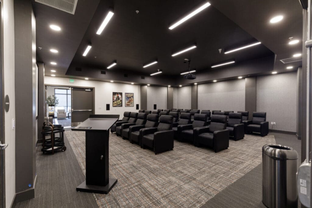 Upscale theater room featuring black  seats, a sleek podium, and modern lighting, ideal for vibrant community events.