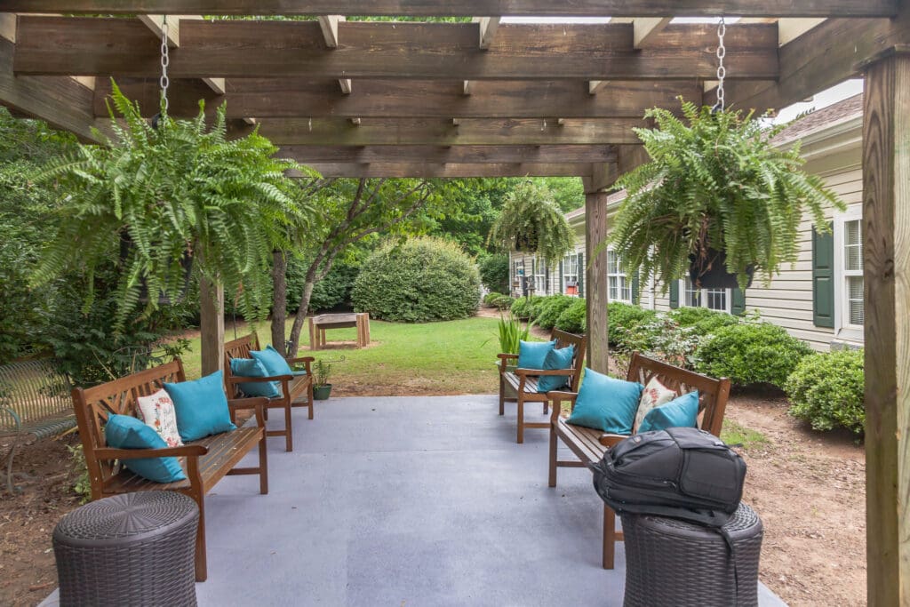w5uIAh7NOY-_MG_7719-1024x683 - Grace Management The Willows of Easley outdoor sitting area with brown benches and white and turquoise throw pillows on them.