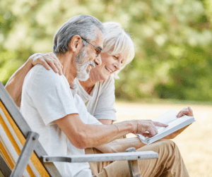 Senior couple sitting in chairs outside reading