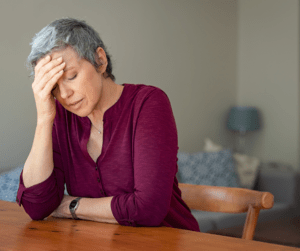 Upset woman sitting with her hand on her forehead