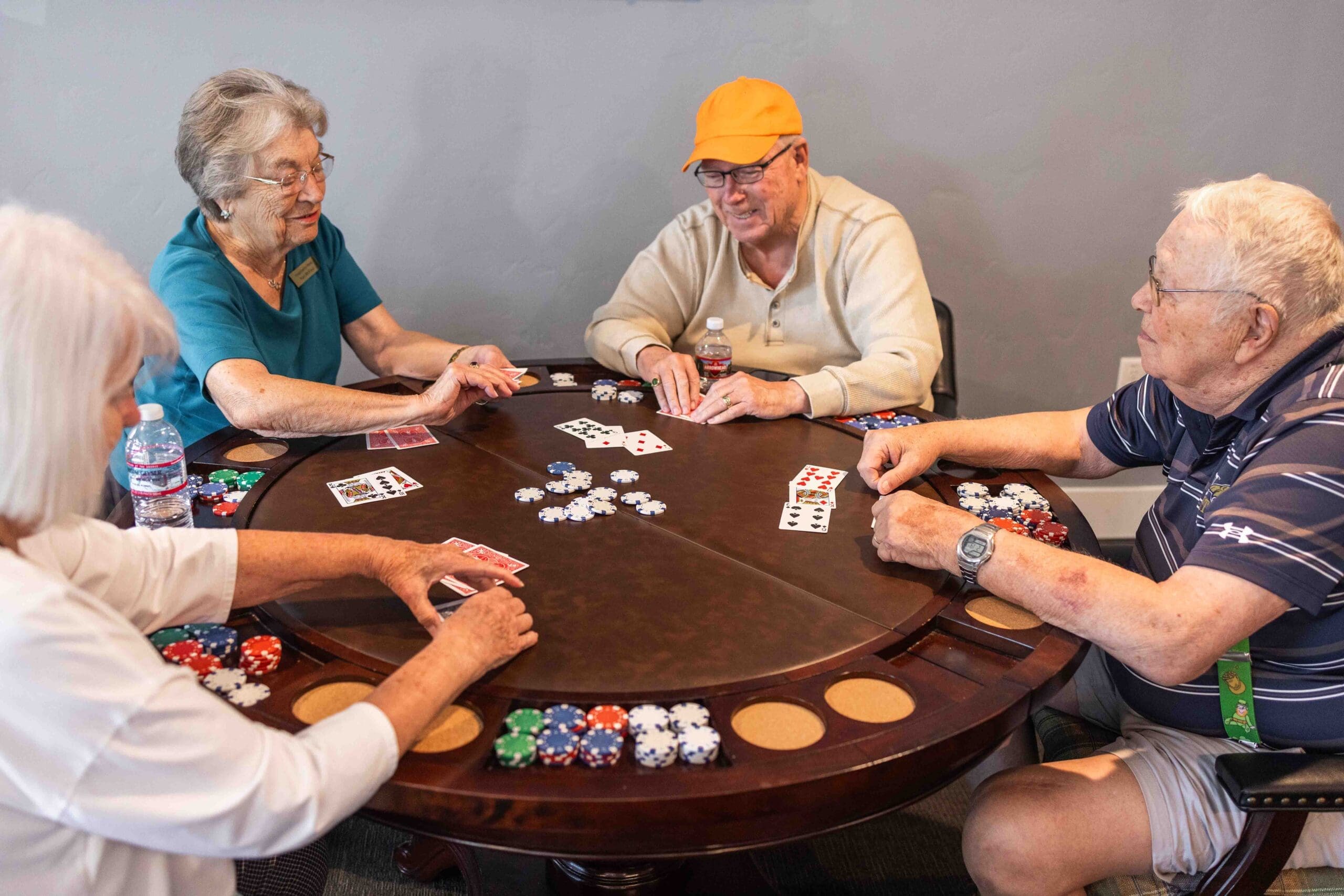 CU7A6908-scaled - Grace Management A group of seniors sit at a poker table engaged in a game at The Summit of Coralville.